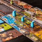Board game with colorful tiles and player pieces on a dark surface