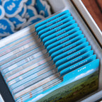 A close-up of a card game box tray holding many blue and white cards, with a row of bright blue tabs labeled by country names such as Turkey, Iran, Japan, and Aztec.